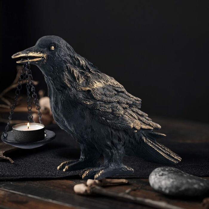 Black raven tealight candle holder on a dark wooden altar table in a moody dark Nordic interior