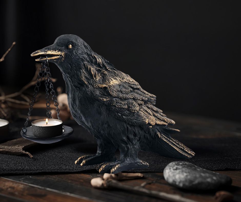 Black raven tealight candle holder on a dark wooden altar table in a moody dark Nordic interior